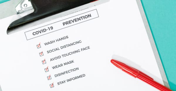 Top view of a COVID-19 prevention checklist and safety equipment
