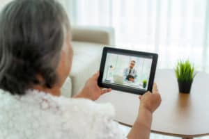 Back view of elderly woman making video call with her doctor wit