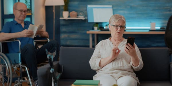 Senior person holding smartphone to talk on teleconference call